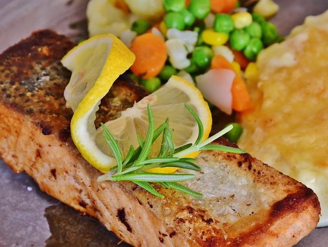 Grilled salmon fillet served with lemon slices and vegetables